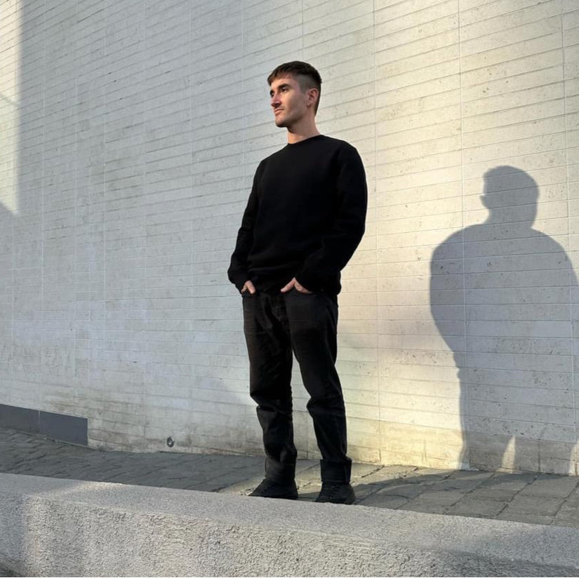 Luxury streetwear male model wearing black crewneck sweatshirt ‘reflect’ in urban setting