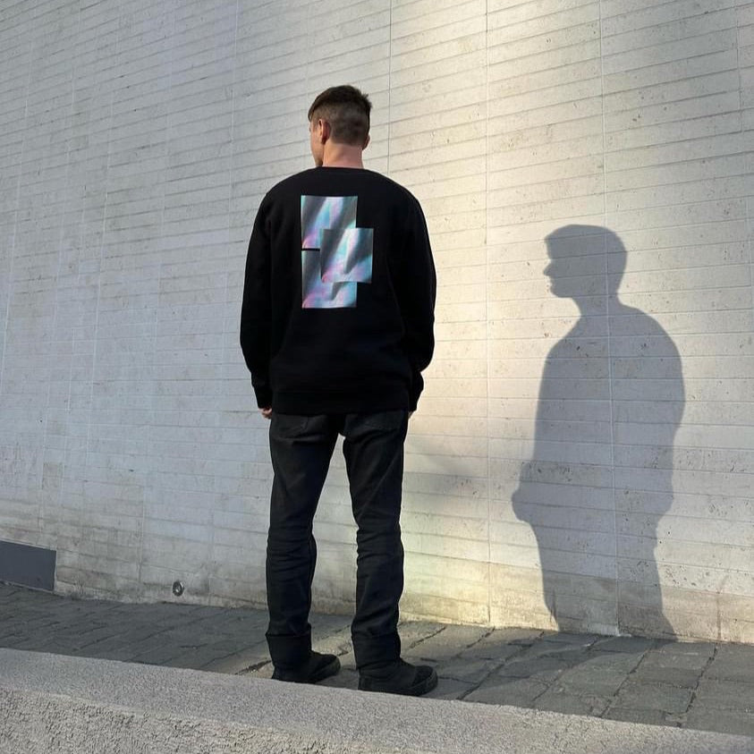 Back of model standing in urban street wearing luxury streetwear black crewneck with graphic sweatshirt back print