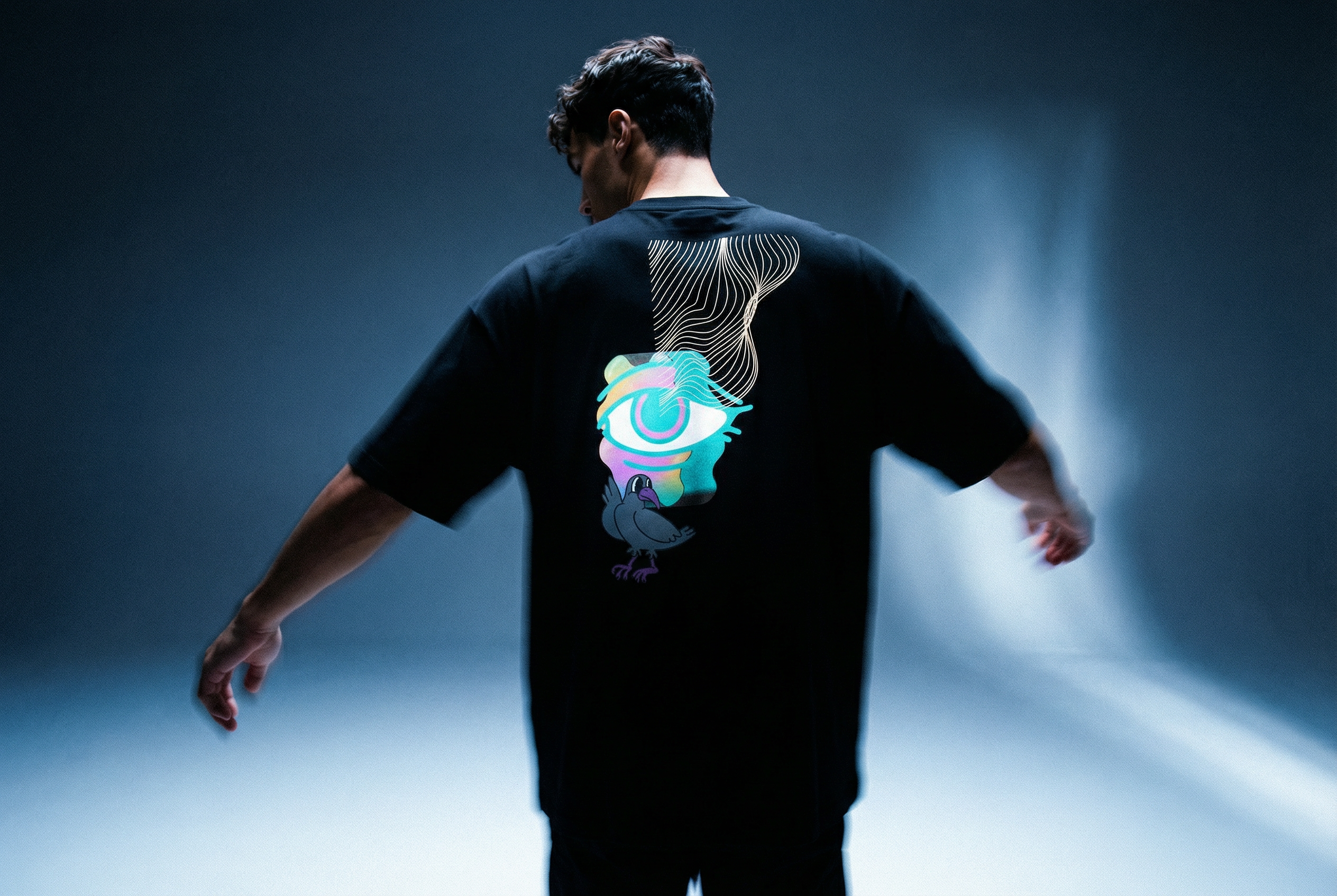 Person wearing a black t-shirt with a colorful graphic design in luxury streetwear urban clothing aesthetic