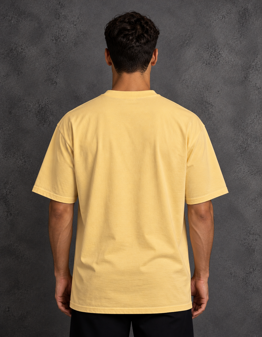 Back view of a model wearing a plain golden yellow t-shirt with short sleeves and a straight hem.