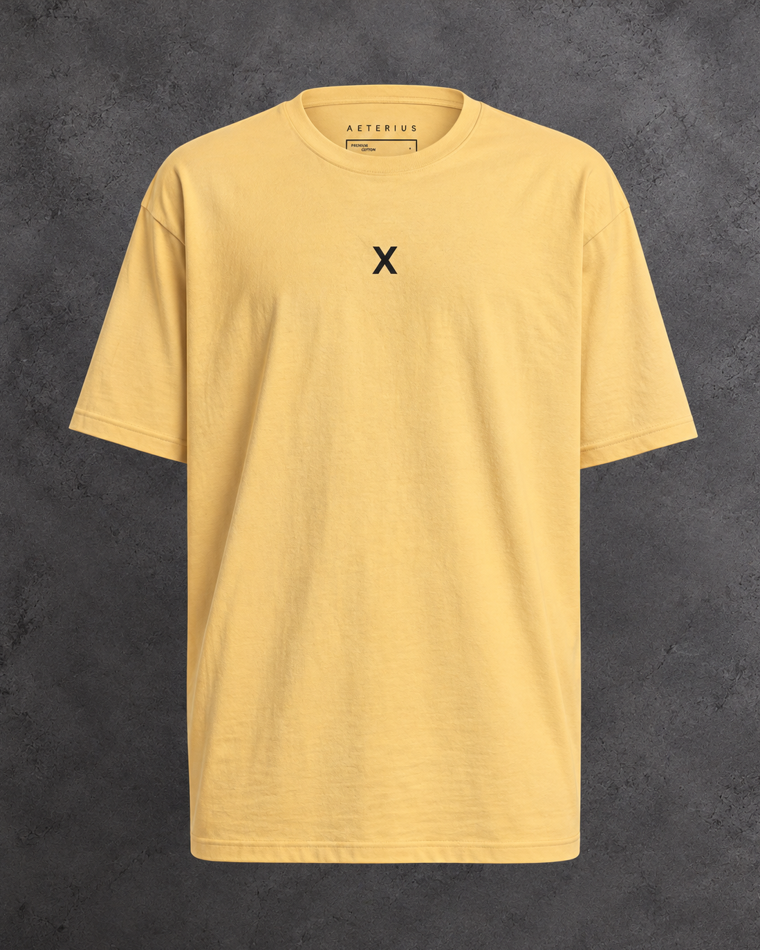 Golden yellow crew-neck t-shirt with a small black X on the chest, displayed against a gray background.