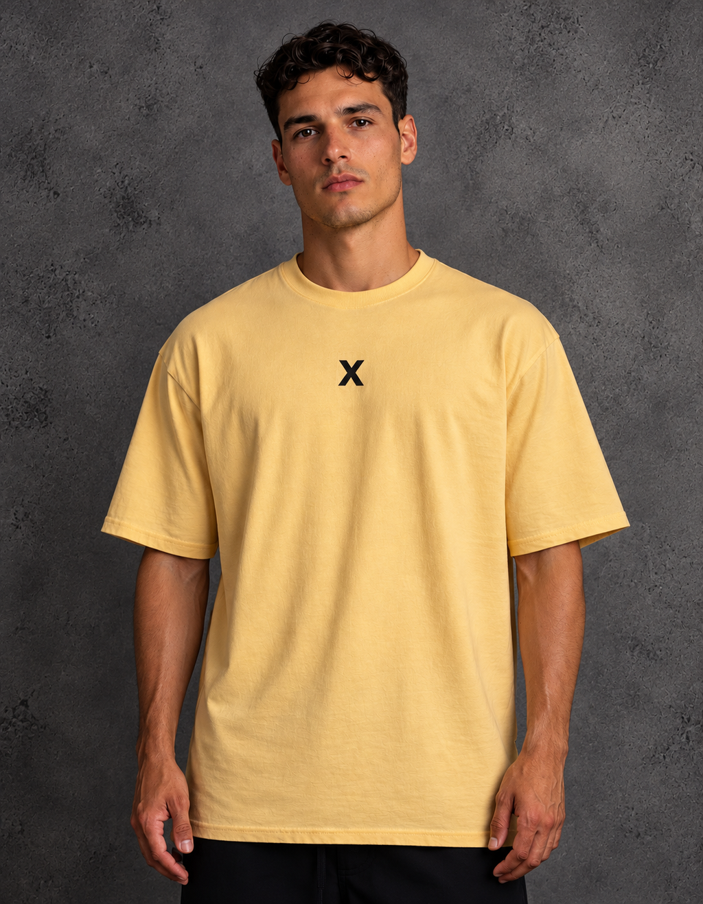 Model wearing a golden yellow t-shirt with a small black X centered on the chest, a crew neck and short sleeves.