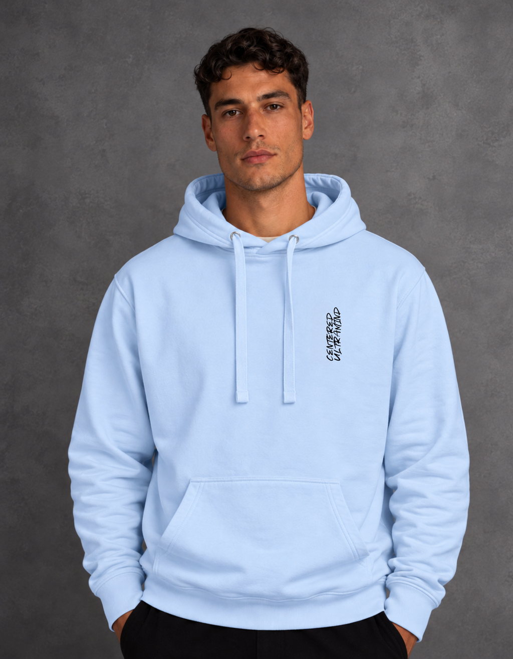 Model wearing a light blue hoodie with small vertical chest lettering, matching drawstrings and a kangaroo pocket.