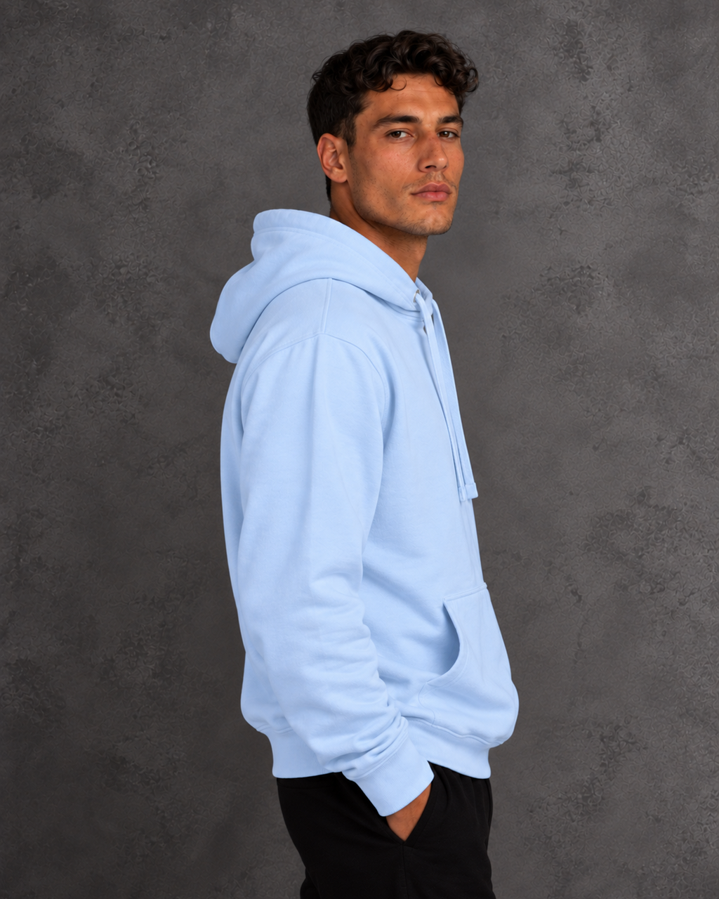 Side view of a model wearing a light blue hoodie with matching drawstrings and a front pouch pocket against a gray background.