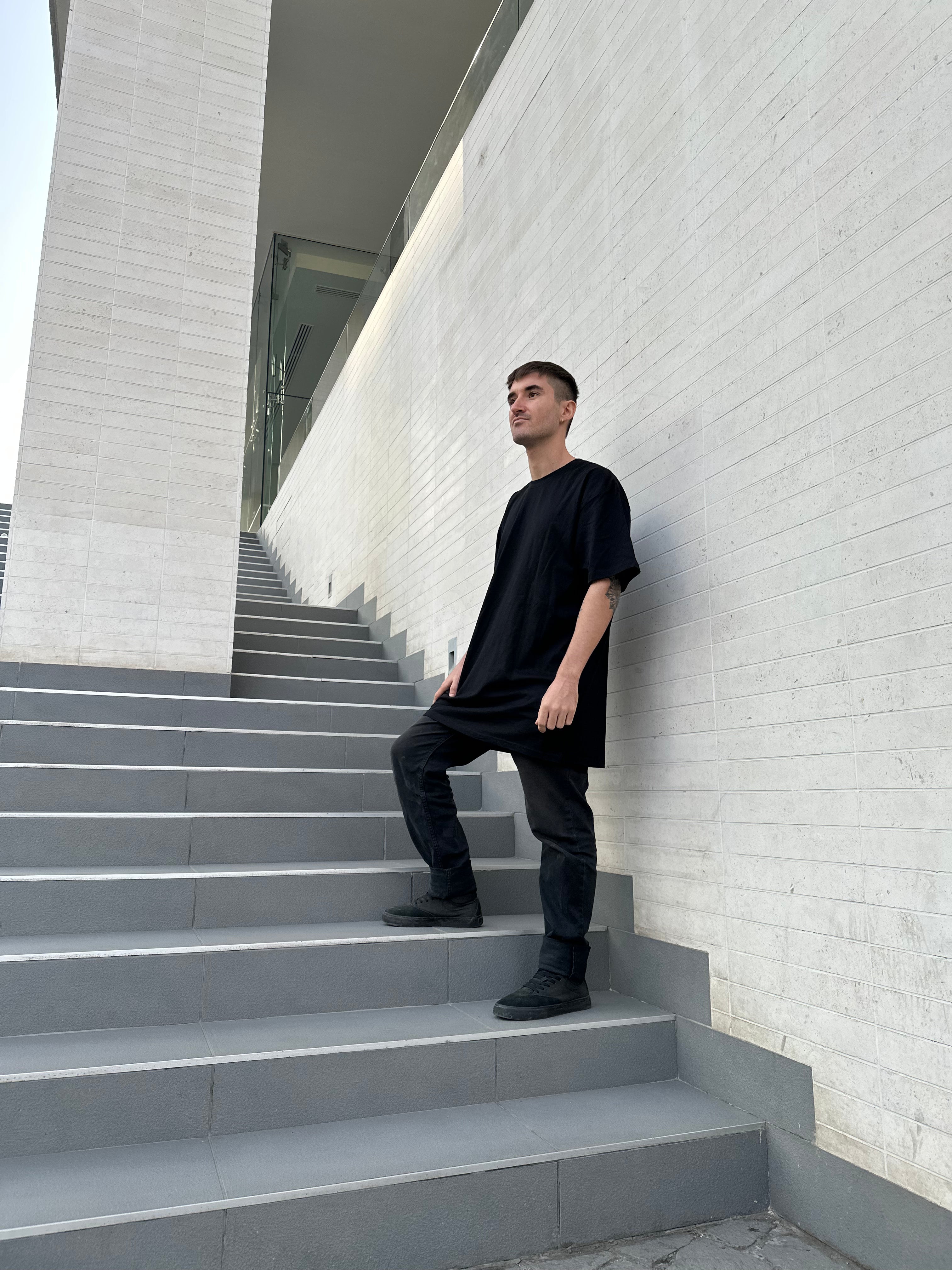 Luxury streetwear and urban clothing model standing on staircase wearing black oversized t-shirt