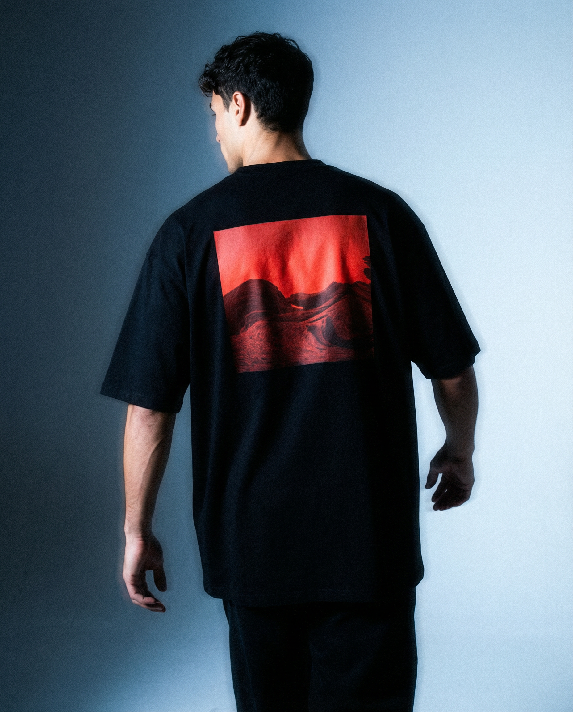 Model wearing a black t-shirt with a red graphic back print in luxury streetwear urban clothing AETERIUS shoot