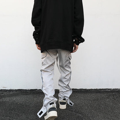 back of streetwear ankle snap light grey cargo pants, luxury streetwear model facing white wall 