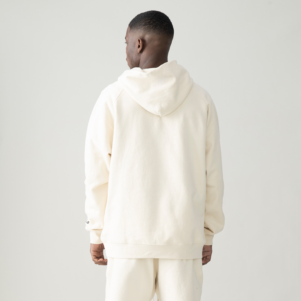 back view of model wearing off white hoodie and off white pants, his face turned to the side