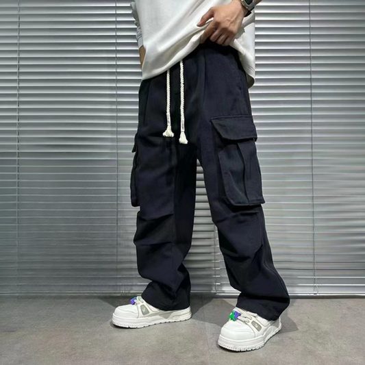 model from abs down in mens black cargo pants with white drawstrings untied, lifting sweatshirt to show cargo pants, cotton material, front view