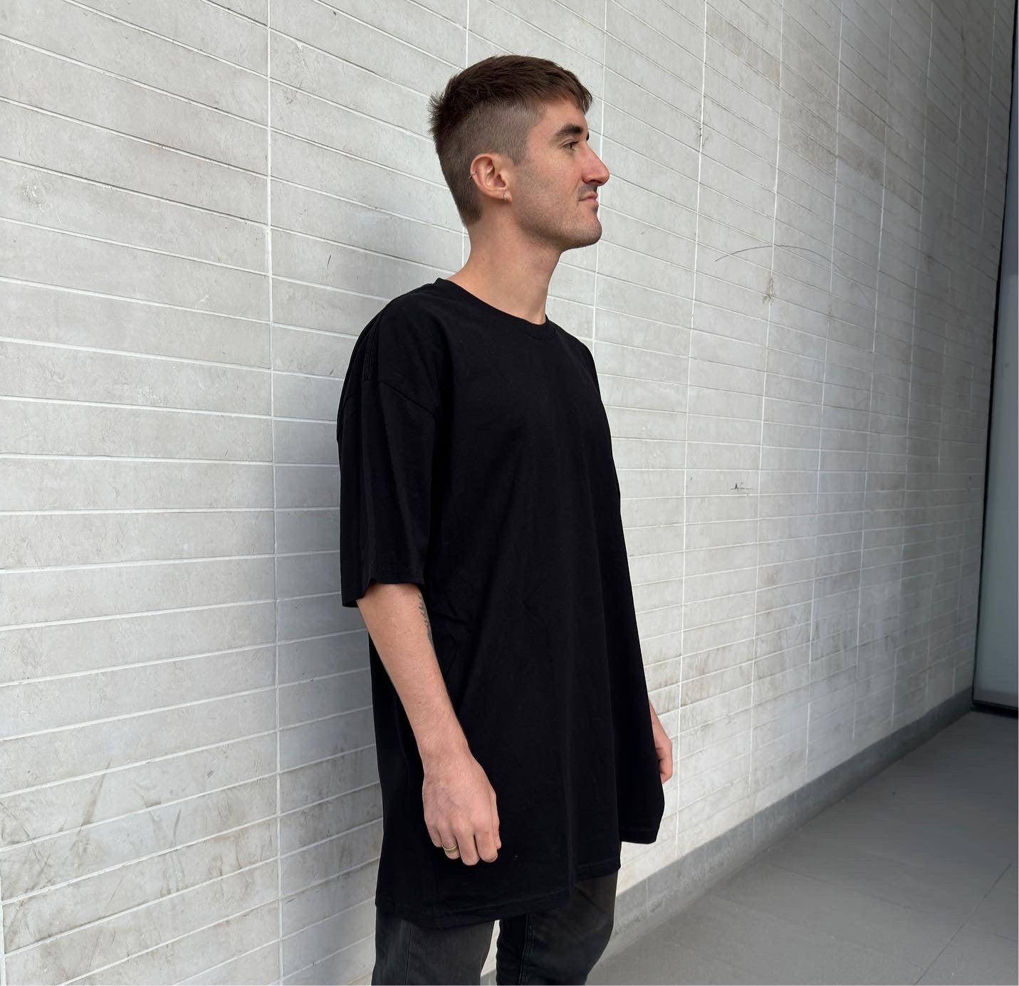 Model from side perspective wearing black oversized t-shirt in luxury streetwear aesthetic