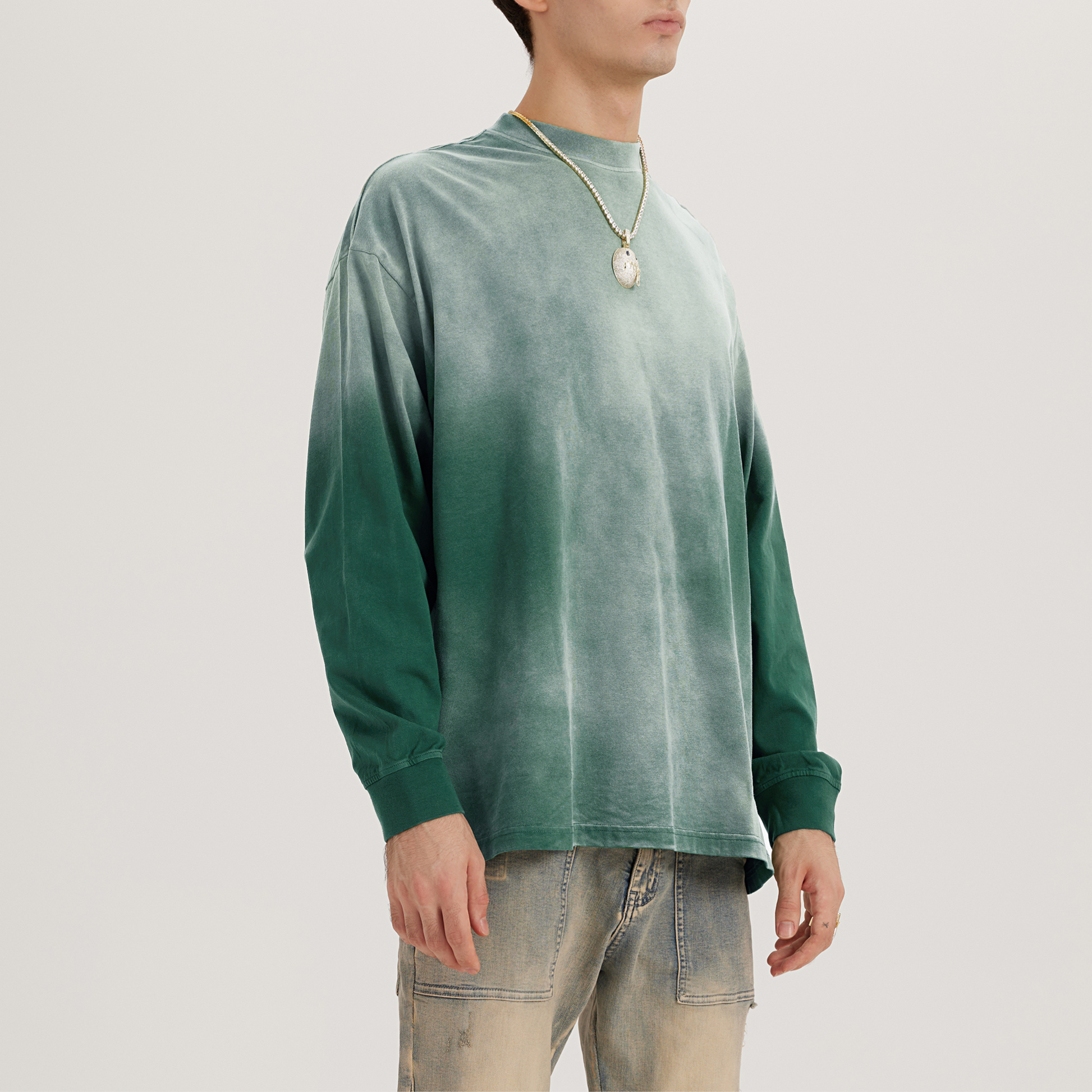 front left view of green streetwear crewneck with faded dyed hues, model with denim jeans and necklace