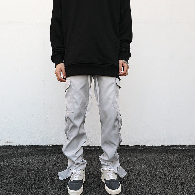 model's front wearing black hoodie and light grey cargo pants in luxury streetwear aesthetic, standing against white wall