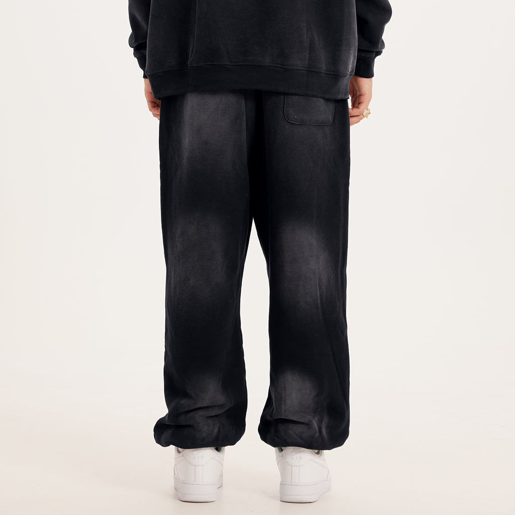 luxury streetwear black oversized pants with washed black effect, AETERIUS streetwear pants in a baggy sweapants fit. Model wearing white shoes
