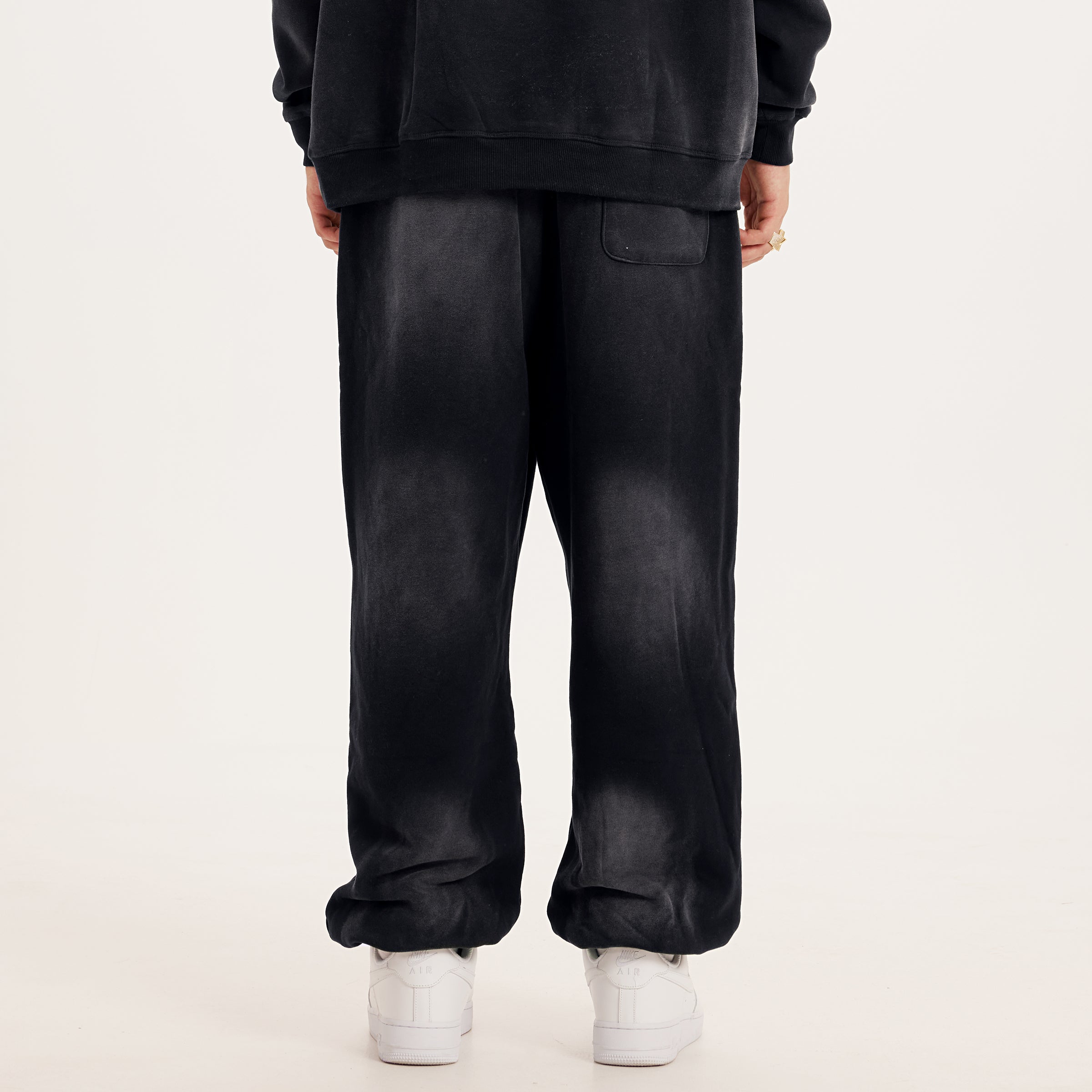 luxury streetwear black oversized pants with washed black effect, AETERIUS streetwear pants in a baggy sweapants fit. Model wearing white shoes
