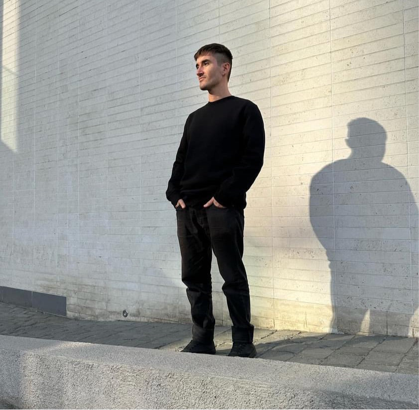 Luxury streetwear male model wearing black crewneck sweatshirt ‘reflect’ in urban setting