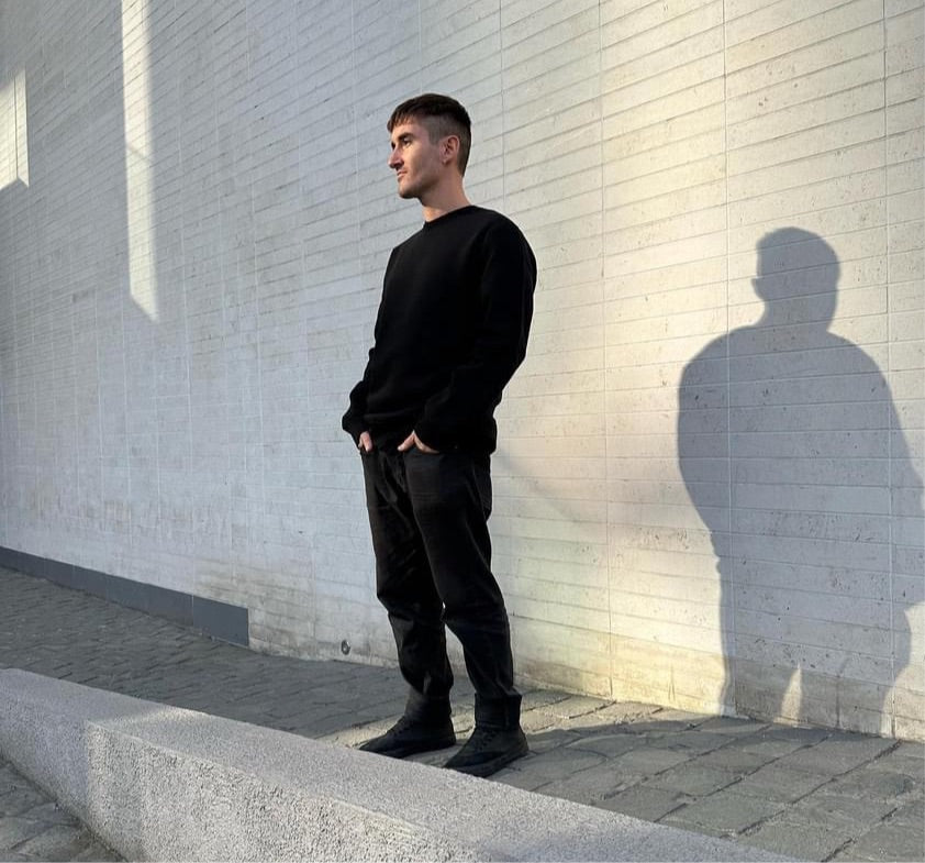 Menswear luxury streetwear model wearing black crewneck sweatshirt in urban setting