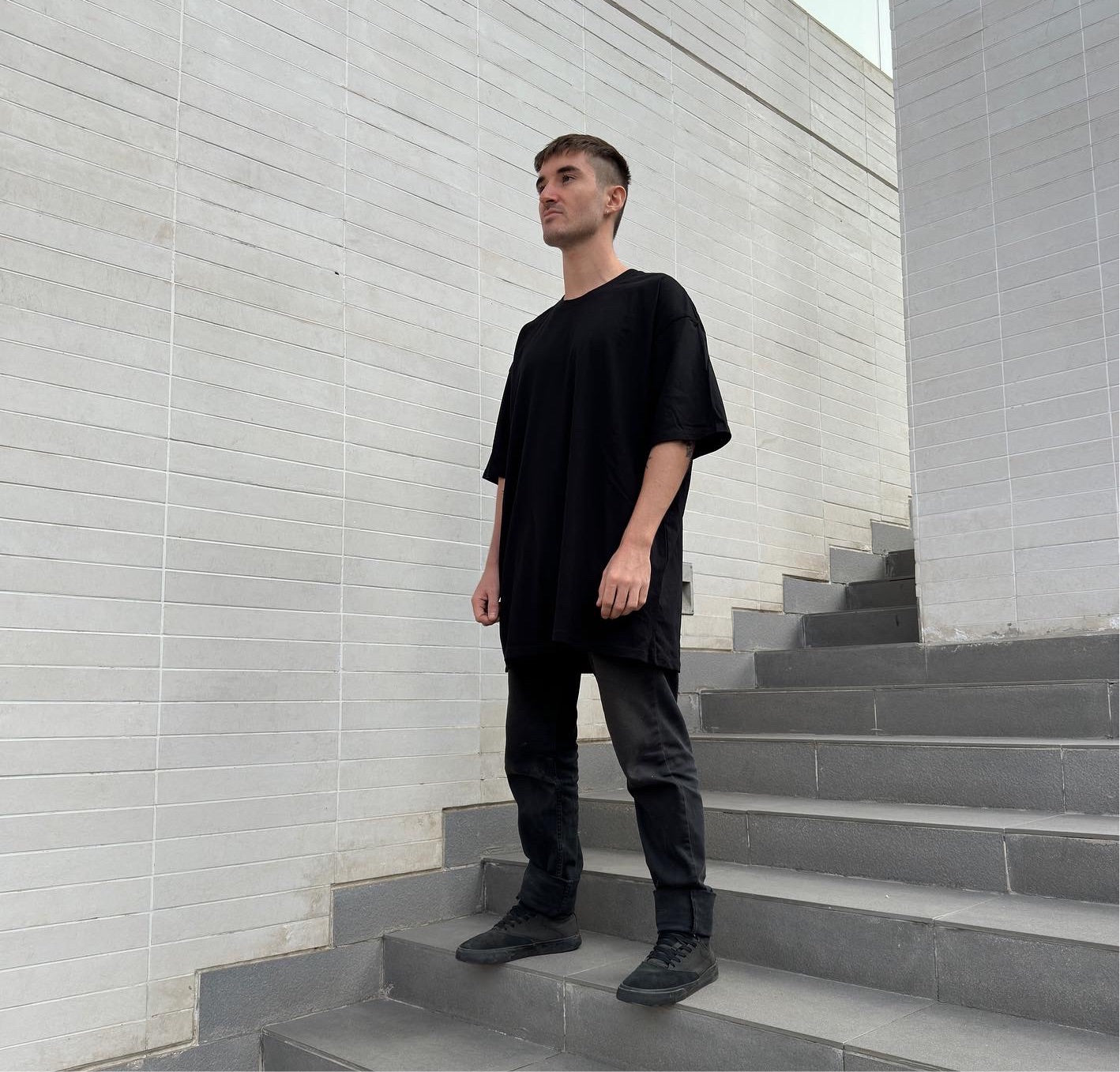 oversized black t-shirt luxury streetwear model standing on staircase 