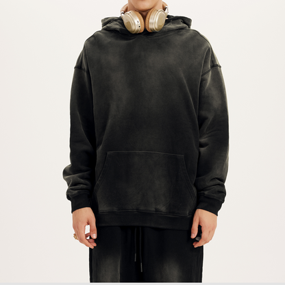 a model with headphones wearing oversized drop shoulder black hoodie in a faded black streetwear hoodie aesthetic