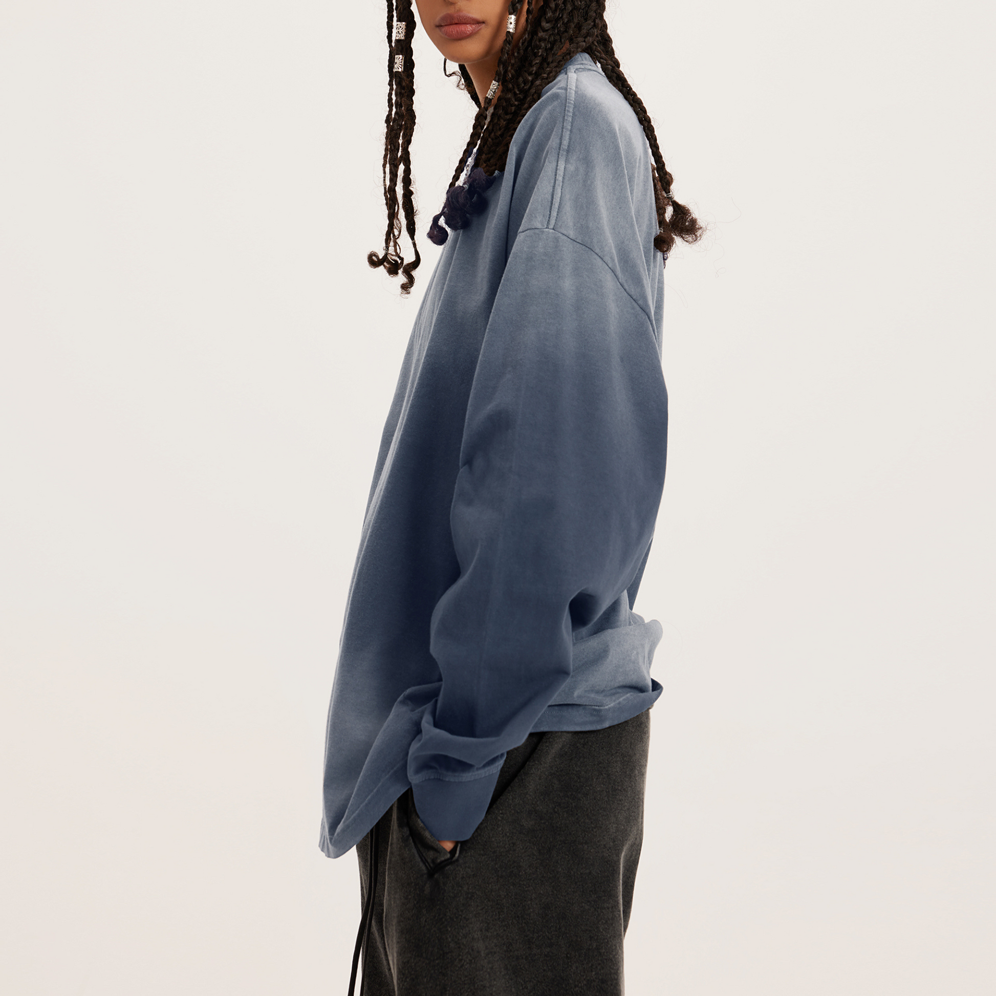 side view of washed grey oversized crewneck, model with hands in her pocket; hair dreads 