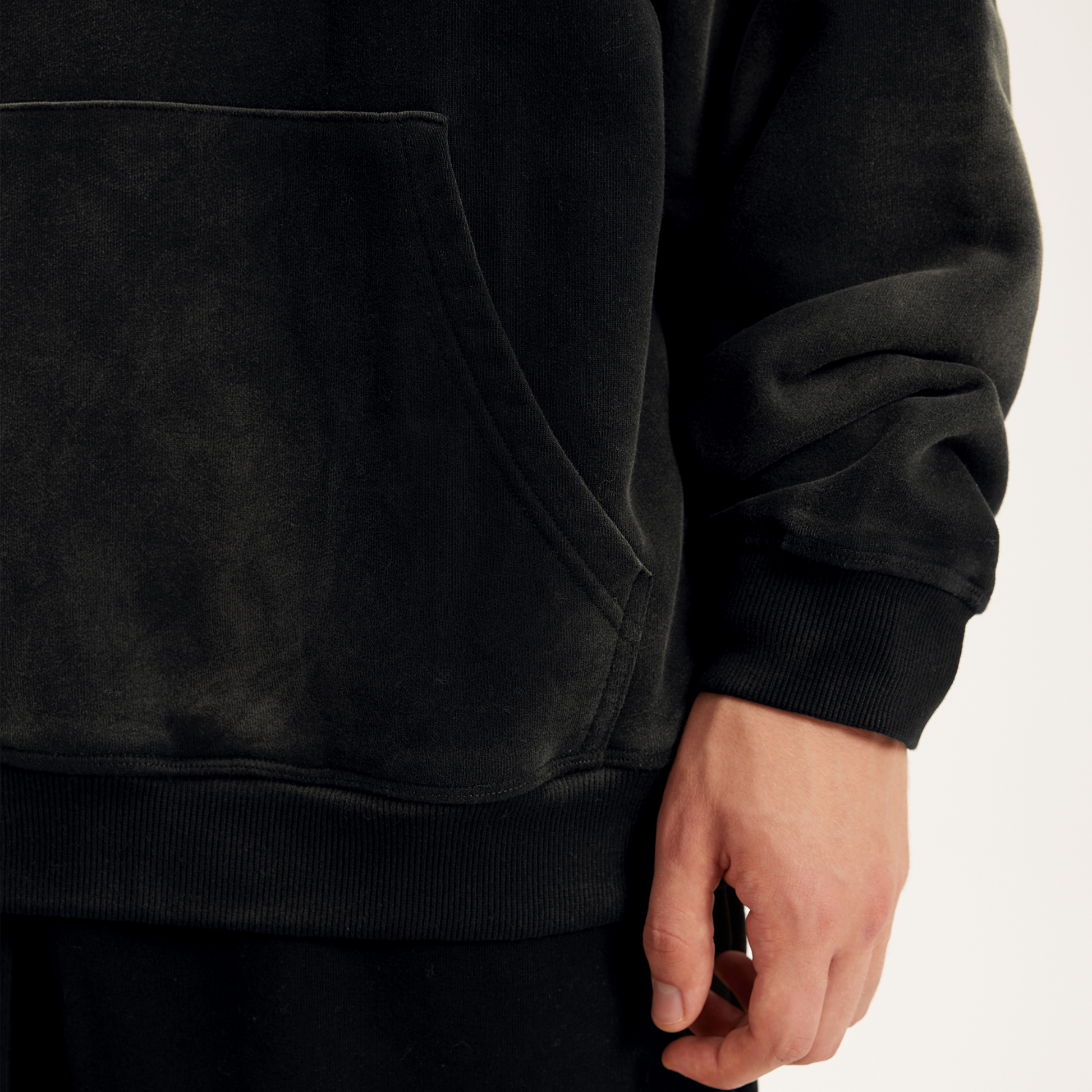 zoomed in left lower details of dyed black hoodie, streetwear hoodies collection product details