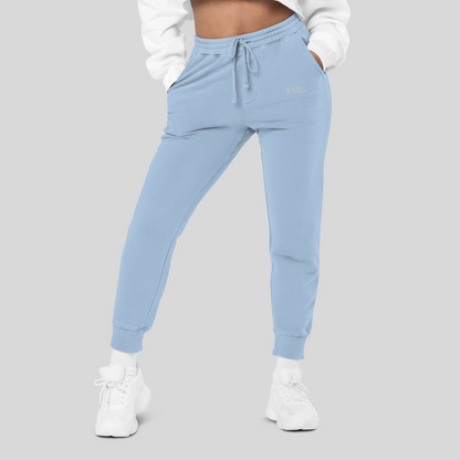 front view of womens light blue joggers, blue streetwear sweatpants with front pockets and small 'solar flashing' white embroidery beneath left pocket in white